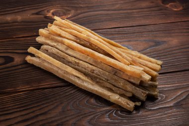 Ahşap arka planda kurutulmuş tuzlu ton balığı şeritlerinin yakın çekimi. Bira atıştırmalıkları, restoran menüsü, tuzlu deniz ürünleri..