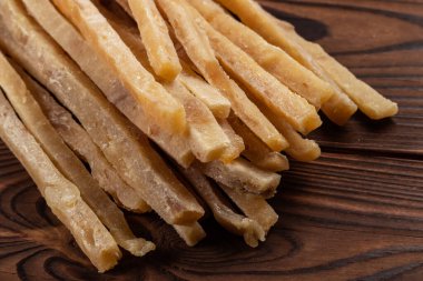 Ahşap arka planda kurutulmuş tuzlu ton balığı şeritlerinin yakın çekimi. Bira atıştırmalıkları, restoran menüsü, tuzlu deniz ürünleri..