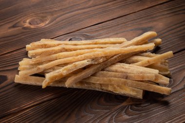 Ahşap arka planda kurutulmuş tuzlu ton balığı şeritlerinin yakın çekimi. Bira atıştırmalıkları, restoran menüsü, tuzlu deniz ürünleri..