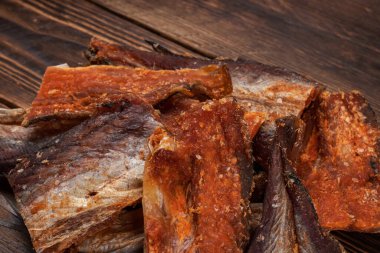 Ahşap zeminde kurutulmuş balık parçaları. Kuru biberli Pollack. Biberli Amber..