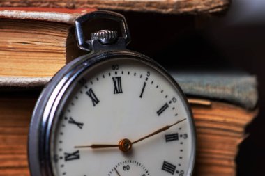 Vintage pocket watch on the background of old books.