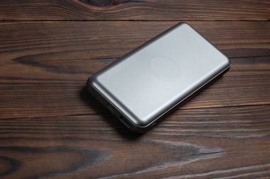 Power bank for charging mobile devices on wooden background. External battery for mobile devices