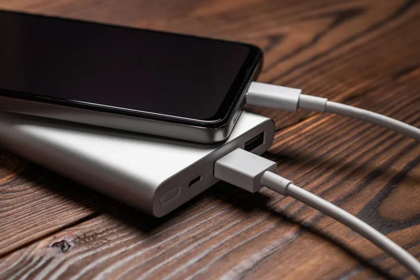 stock image Powerbank and charge smartphone on wooden table.