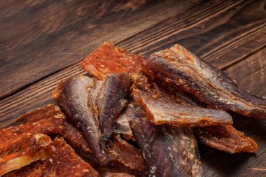 Ahşap zeminde kurutulmuş balık parçaları. Kuru biberli Pollack. Biberli Amber..