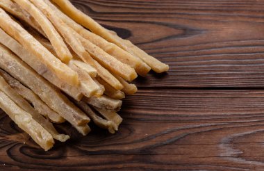 Ahşap arka planda kurutulmuş tuzlu ton balığı şeritlerinin yakın çekimi. Bira atıştırmalıkları, restoran menüsü, tuzlu deniz ürünleri..