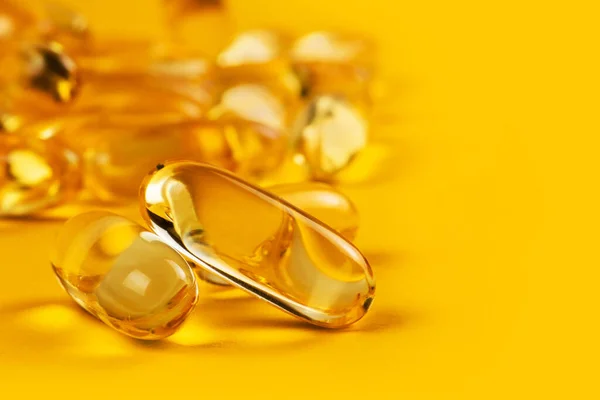 双子胶囊在黄色背景上的Omega 3和其他许多在模糊背景上的胶囊 保健概念 — 图库照片