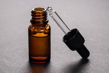 Siyah arka planda pipeti olan kozmetik şişesi.