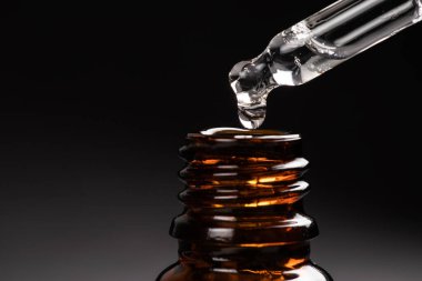 Gerilmiş damlalar damlacıktan şişeye sızar karanlıkta.