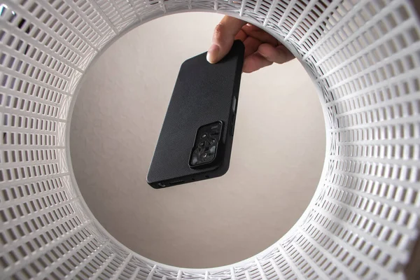 Adamın biri çalışmayan bir akıllı telefonu çöp kutusuna atıyor. Çöp kutusundan son görüntü. Çöplerle gezegenin geri dönüşümü ve kirliliği sorunu.