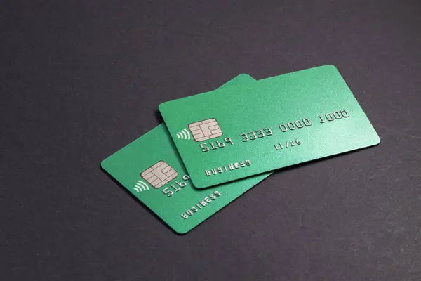 Two green credit cards on dark background