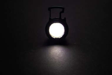 LED Flashlight anahtarlık ve karanlıkta bir ışık demeti. Karanlık masa üzerinde parlak projeksiyonu olan modern bir lamba.