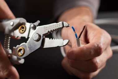 Ev şebekesindeki kabloları onarıp güncellerken elektrik kablolarının ucunu sökmek için striptizci aletinin kullanılması. Elektrik kurulum işi.