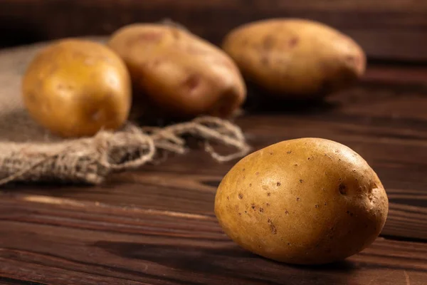 Raw potato food. Fresh potatoes in an old sack on wooden background.