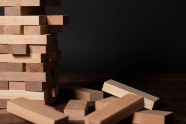 Koyu arkaplanda tahta bloklardan yapılmış Jenga kulesi.
