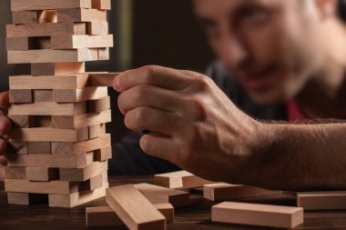Koyu kahverengi masada Jenga oyunu için ahşap bloklar yığan erkek elleri, karantina sırasında evde kalırken, aile aktiviteleri, parti panosu oyun konsepti devre dışı