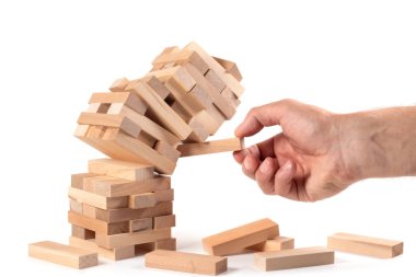 İş adamı, tahta bloğu düşen kuleden kaldırıyor. Tahta jenga oyunuyla risklerin yönetimi ve ekonomik istikrarsızlık kavramı. Şirket işinde başarısızlık ve çöküş