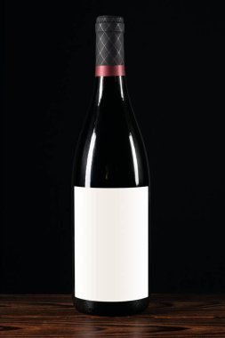 Ahşap arka planda boş etiketli kırmızı şarap şişesi..