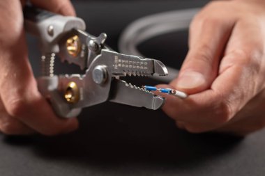 Gri iş eldiveni giyen bir elektrikçi bir striptizciyle elektrik tellerini söküyor.