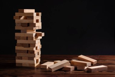 Koyu arkaplanda tahta bloklardan yapılmış Jenga kulesi.
