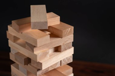 Koyu arkaplanda tahta bloklardan yapılmış Jenga kulesi, metin için boşluk.