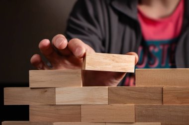 Adam tahta blokları tutuyor Jenga Duvarı inşa et