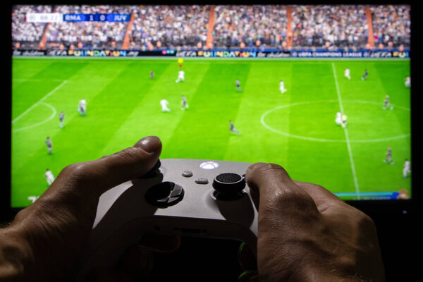 Dnipro, Ukraine, 28 september 2023: Man playing EA FC 24 with Xbox controller on TV screen.