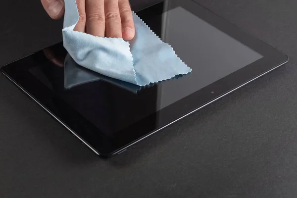 Man\'s Hand Cleaning Digital Tablet Screen With Soft Blue Cloth.