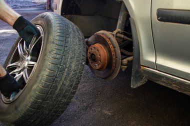 Araba tamiri. Tekerlekleri değiştiriyorum. Mevsimlik lastik değiştirme. Efendi anahtarı iki eliyle direksiyonu kaldırır. Üniformalı bir usta.