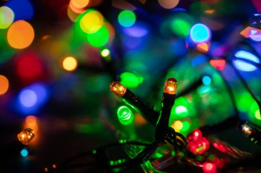 Işıklı ve bedava metin alanlı bir Noel arkaplanı. Noel ışıkları sınırda. Ahşap arka planda parıldayan renkli Noel ışıkları. Yeni yıl. Noel zamanı. Dekorasyon. Çelenk.