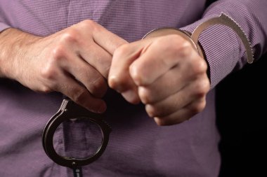 Suçlu hapishaneden serbest bırakıldı. Beraat, masum bir sanığa verildi. Eller kelepçeleri çözüyor. Tutuklanan kişinin erkek ellerinde kelepçeleri açın. Gerçek polis kelepçeleri.