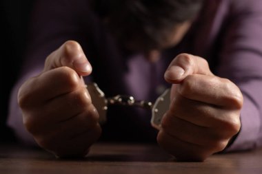 Elleri kelepçeli şık giyimli bir adam, bir suçlu..