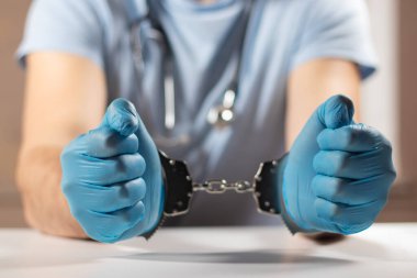 Doktor kelepçeli, eller yakın plan, tıbbi yozlaşma, rüşvet, suç kavramı.
