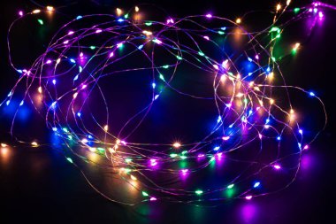 Noel ışıkları arka planı, kopyalama alanı. Karanlık yüzeyde tatil parlayan çelenk sınır manzarası. Noel ağacı süslemeleri, kış tatili aydınlatmaları