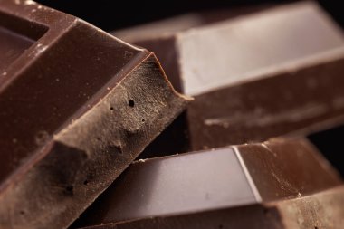 Kırık çikolata. Çikolata parçaları. Koyu arkaplanda çikolata parçaları