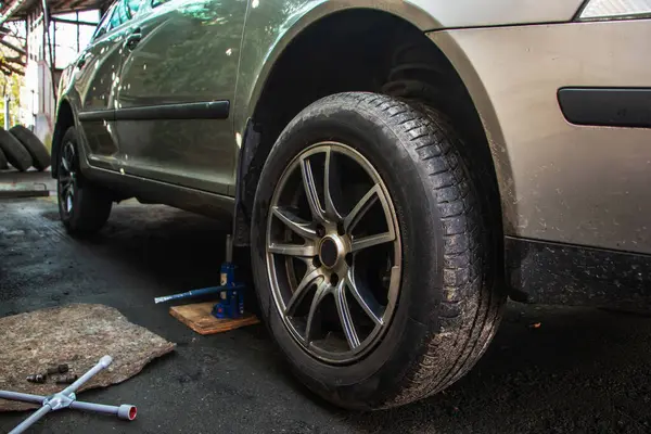 Car lifted by scissor jack without wheel outdoors, closeup. Tire puncture,