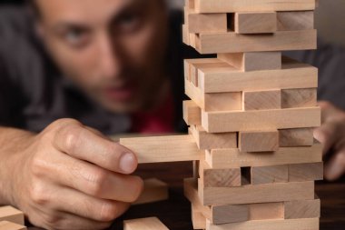 Koyu kahverengi masada oyun için tahta bloklar yığan erkek elleri, karantina sırasında evde kalırken, aile aktiviteleri, parti panosu çevrimdışı oyun konsepti