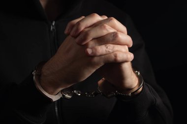 Sandalyede kelepçeli bir adam var. Elleri kelepçeli adamlar suçtan tutuklandı. Elleri arkada, çocuk cezaevi şiddet konseptinde prangalı..