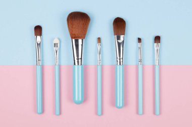 Pembe ve mavi renkli arka planda makyaj fırçaları. Üst bakış açısı, düz yatış