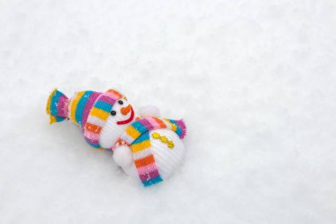 Kışın kar üzerinde atkı ve şapka takan kumaş bir kardan adam.,