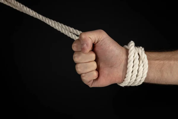 Man\'s hand tied with a rope, vintage effect photo with noise. Pulling man out of a bad situation. Help person conceptual shot. Shackle and restriction.