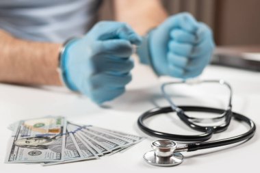 Dolar banknotları ve kelepçeleri olan bir doktor. Tıbbi yolsuzluk, rüşvet, suç kavramı.