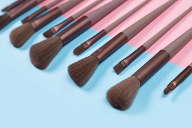 Kozmetik ve güzellik. Mavi arkaplanda makyaj fırçaları ayarlandı.