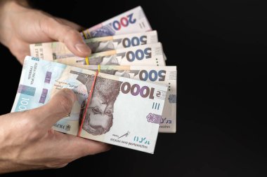 Karanlık arka planda Ukrayna parası tutan adamlar, yakın plan..