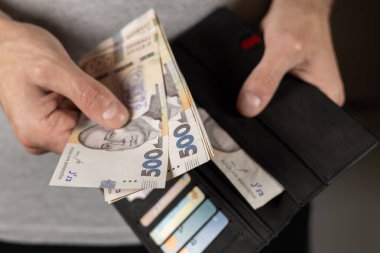 500 hryvniadan oluşan banknot erkek elinde. Üzerinde Ukrayna parası ve kredi kartları olan gri cüzdan..