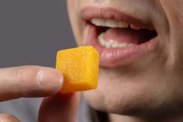Men hold Dried and candied mango cube. Vegetarian food concept.