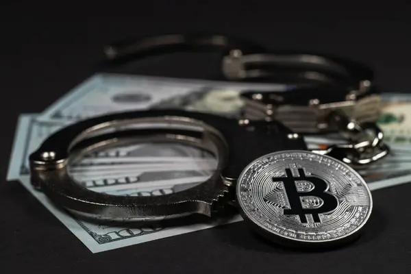 stock image Symbolic coins of bitcoin and stack of bitcoin coins and metall handcuffs on banknotes of one hundred dollars. Exchange bitcoin for a cash dollar, but be a law-abiding citizen.