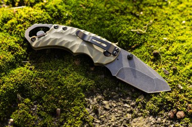 Yosun arka planında hayatta kalmak için taktik katlama bıçağı..