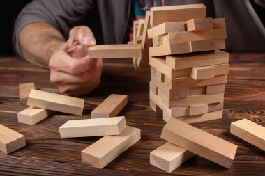 İş adamı, tahta bloğu düşen kuleden kaldırıyor. Risk yönetimi ve tahtadan oyun ile ekonomik istikrarsızlık kavramı. Şirket işinde başarısızlık ve çöküş