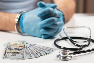 Doktor kelepçe ve para ile. Tıbbi suç.