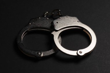 Karanlık masada parlak metal kelepçeler..